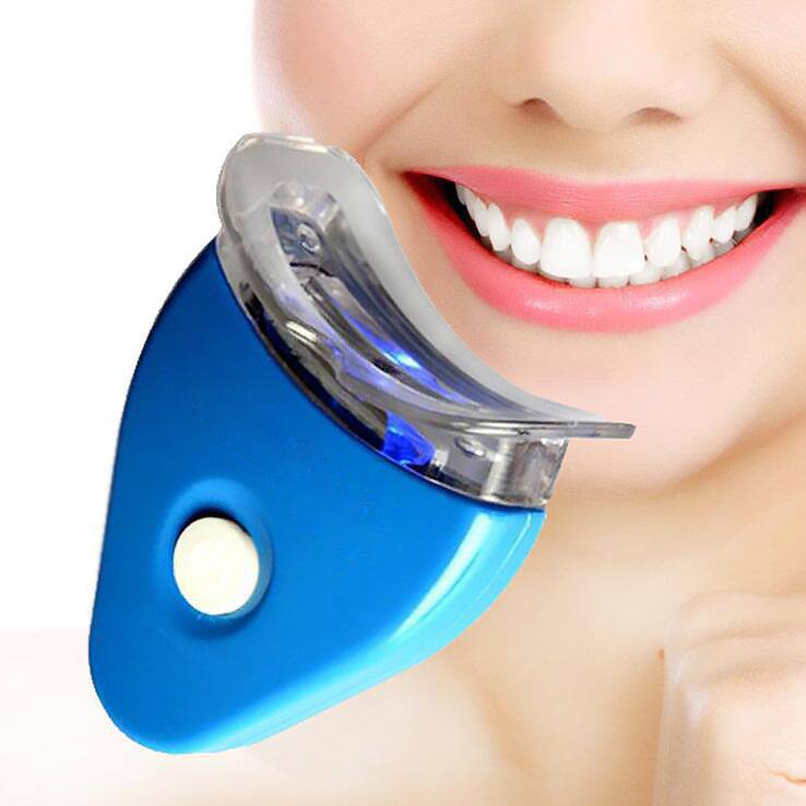 Gel blanqueador dental con férula transparente y dispositivo LED azul brillante, mostrado junto a una sonrisa blanca.