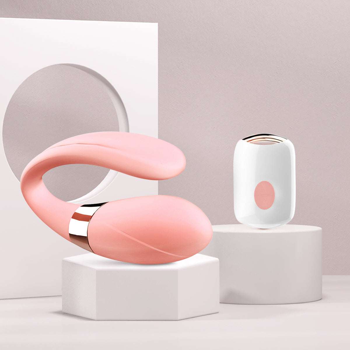 Vibrador para Parejas rosa de silicona suave, con diseño curvo, detalle metálico y control remoto blanco.
